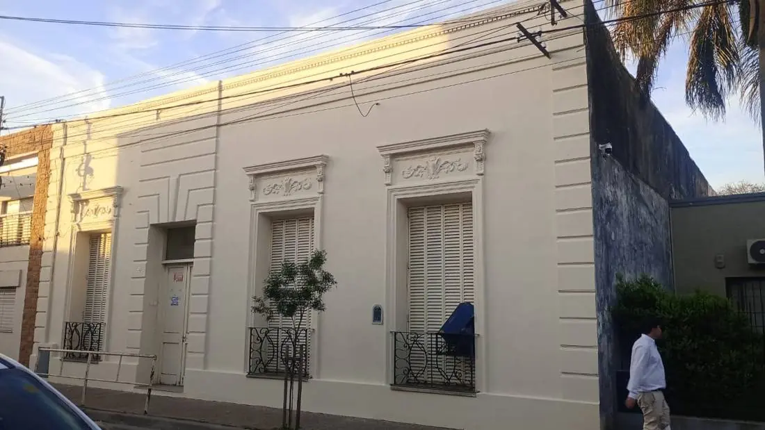 Frente de casena antigua pintado en color crema, con molduras y rejas restauradas
