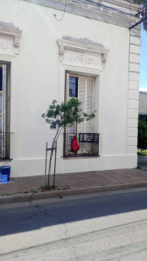 Después: el mismo frente pintado en color crema, con ventana y rejas renovadas