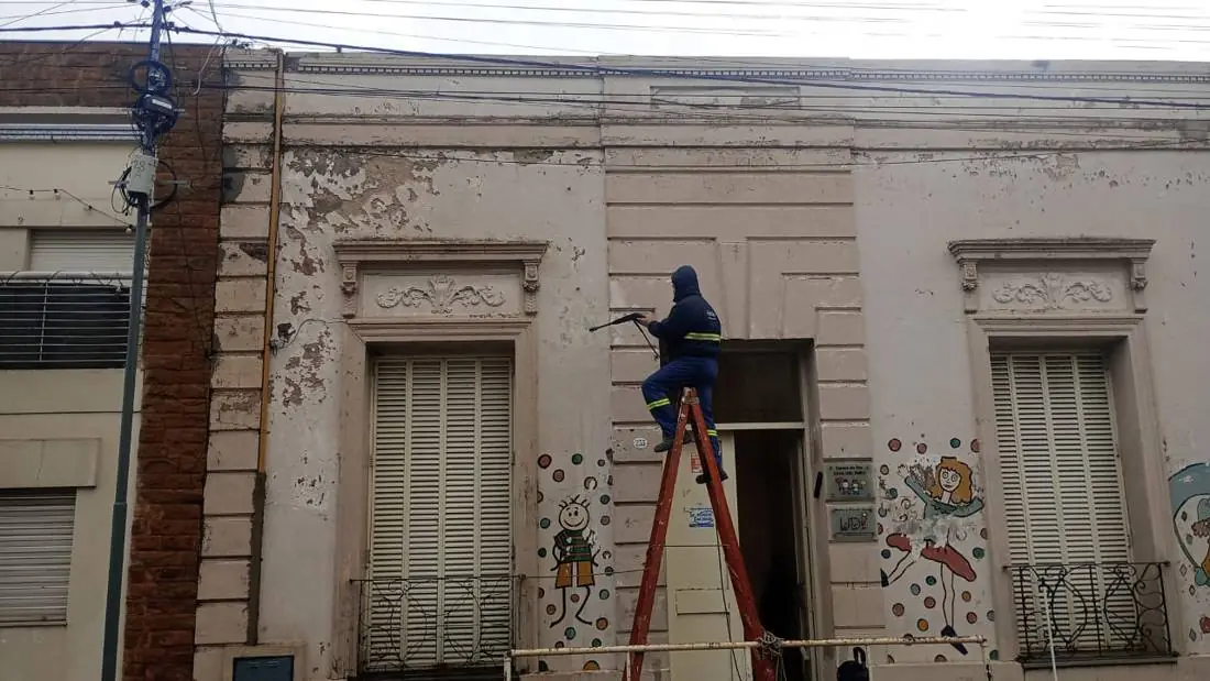 Operario hidrolavando un frente antiguo desde una escalera