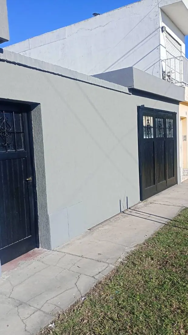 Frente pintado en gris con puerta y portón negros